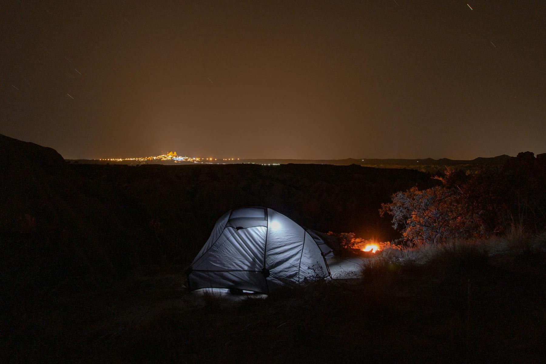 Serene camping scene under a starlit sky with city lights on the horizon. on The Frugal Camper