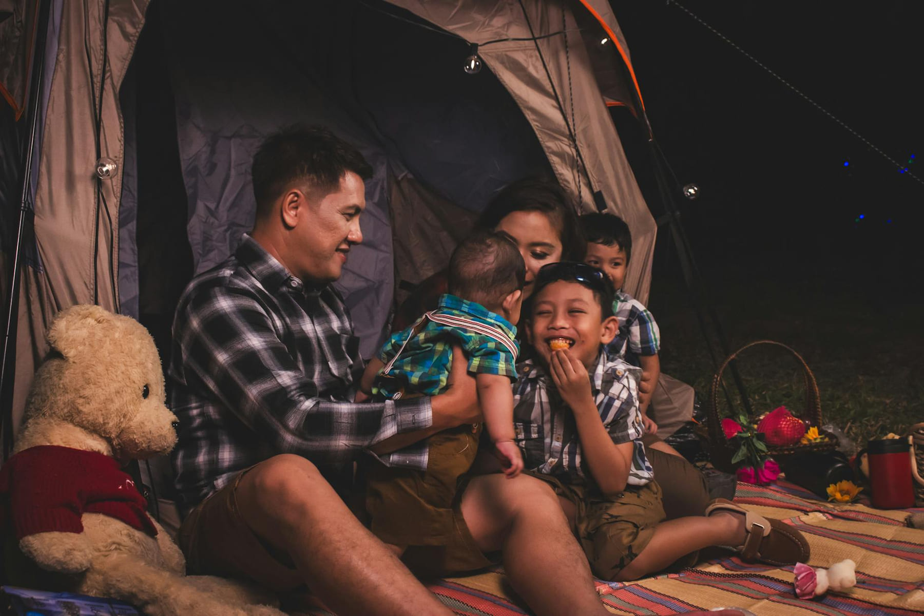 A joyful family enjoying a cozy camping night with snacks in a tent. on The Frugal Camper