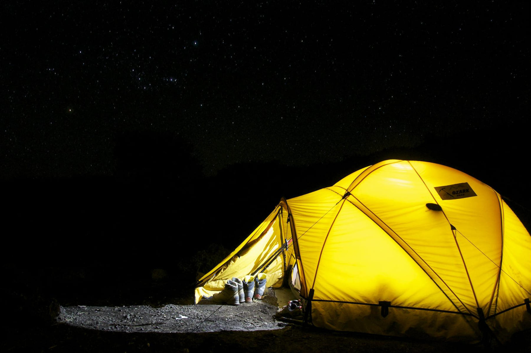 A glowing yellow tent pitched outdoors under a vast, star-filled night sky, capturing the essence of camping adventure. on The Frugal Camper
