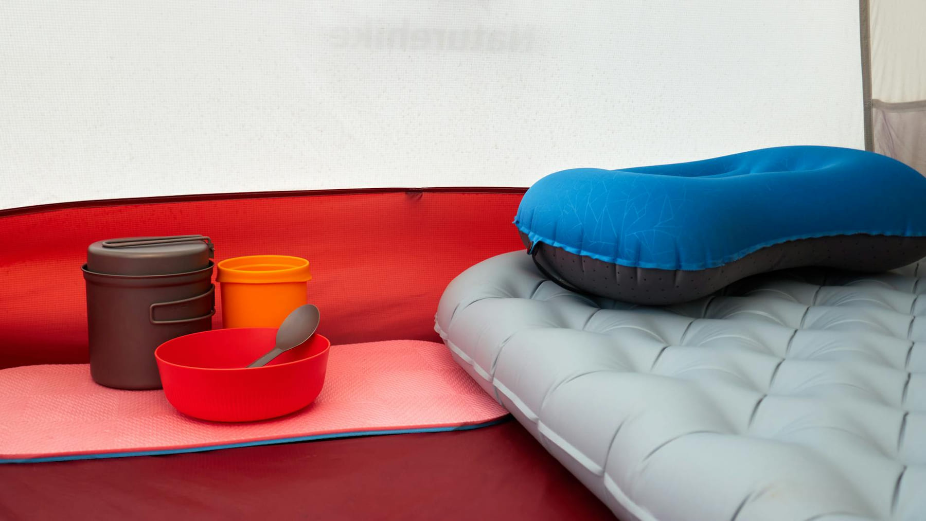 Inside a tent with inflatable pillow, cookware, and sleeping pad, ideal for camping. on The Frugal Camper